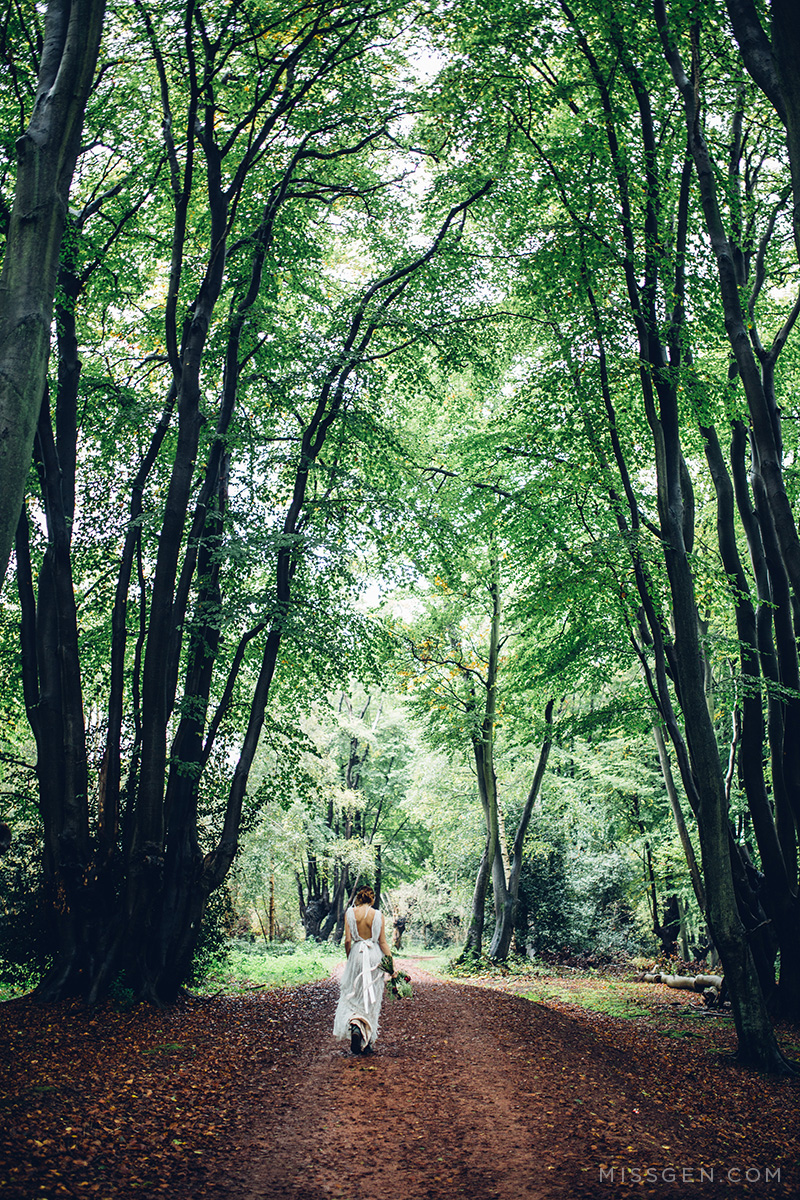Bride walking through the woods wearing Kelly Spence earings and pearl crown and dress by Faith Caton Barber. Woodland elopement inspiration by Miss Gen Photography, London and destination creative reportage wedding photographer.