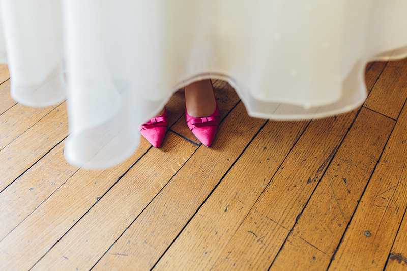 Short vintage polka dot wedding dress with hot pink wedding shoes on wooden floor