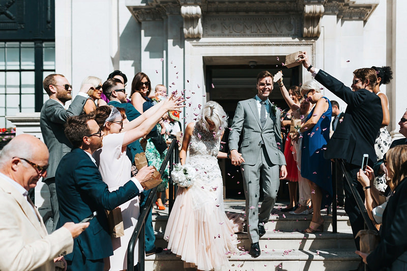 bride and groom with confetti on the steps of islington town hall by london wedding photographer miss gen