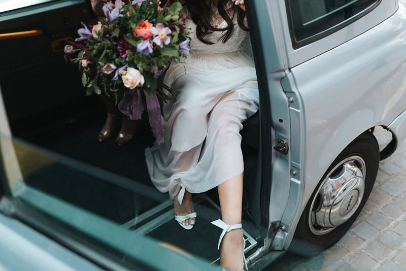 modern reportage style photo of bride getting out of taxi at chelsea town hall in London by natural documentary wedding photographer Miss Gen