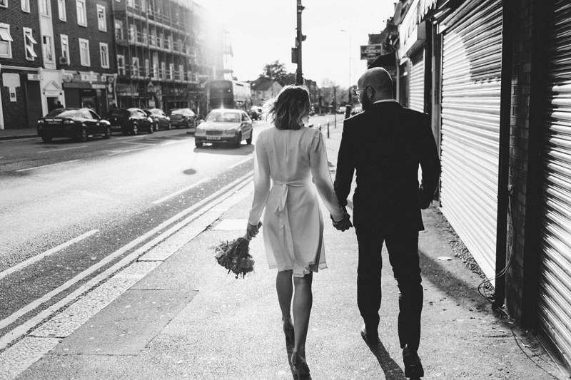 natural relaxed wedding photo of bride and groom walking down East London street by Miss Gen