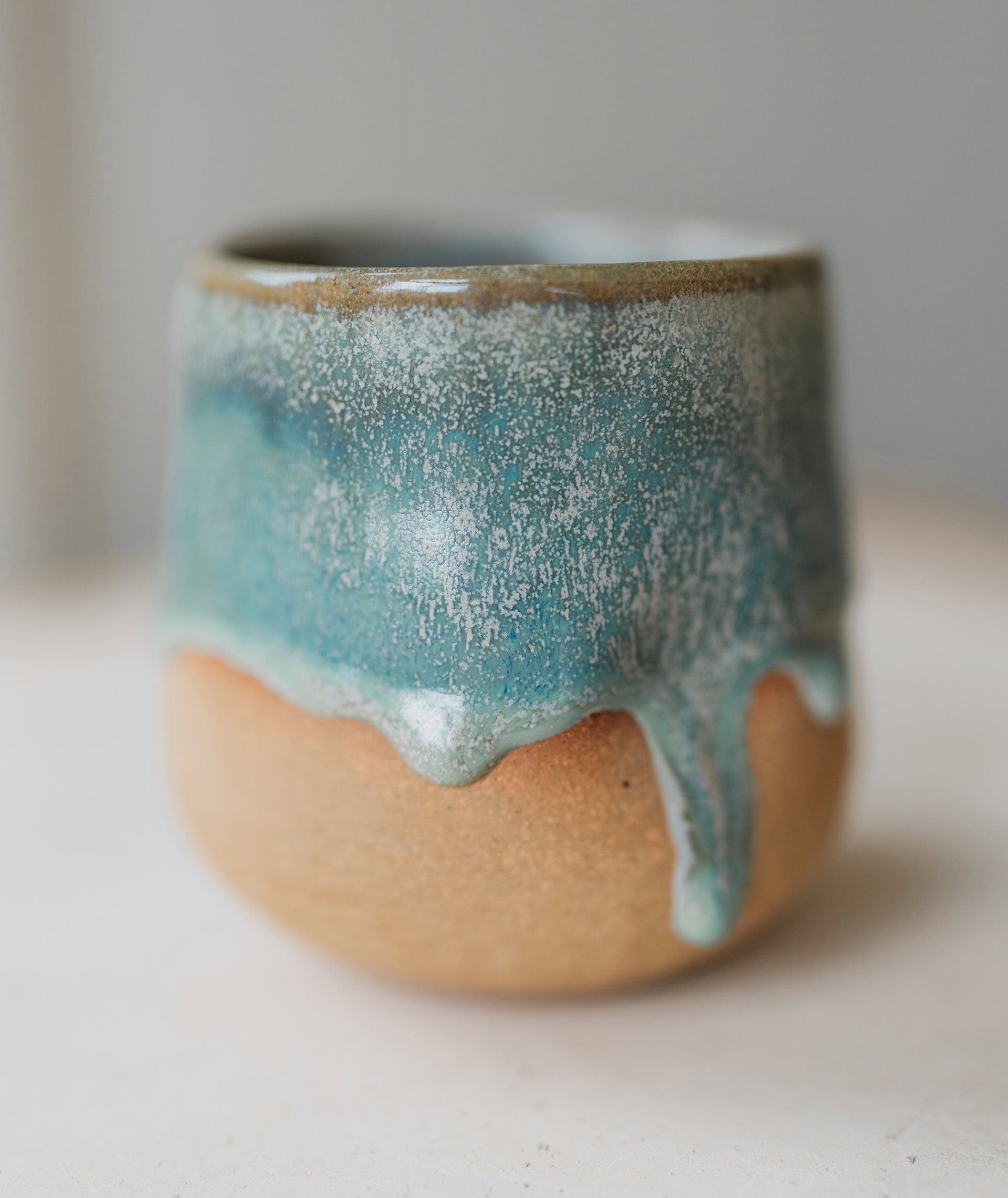 stoneware ceramic cup with drippy glaze in ocean blues and aqua turquoise with crystals and flecks by Genevieve of Miss Gen
